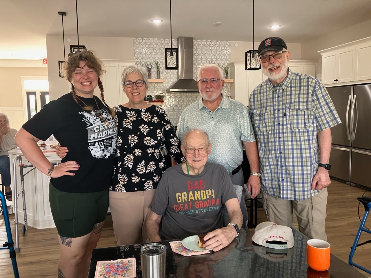 Senior woman seated safely in an assisted living lounge with coffee, showing a supportive environment to prevent falls.